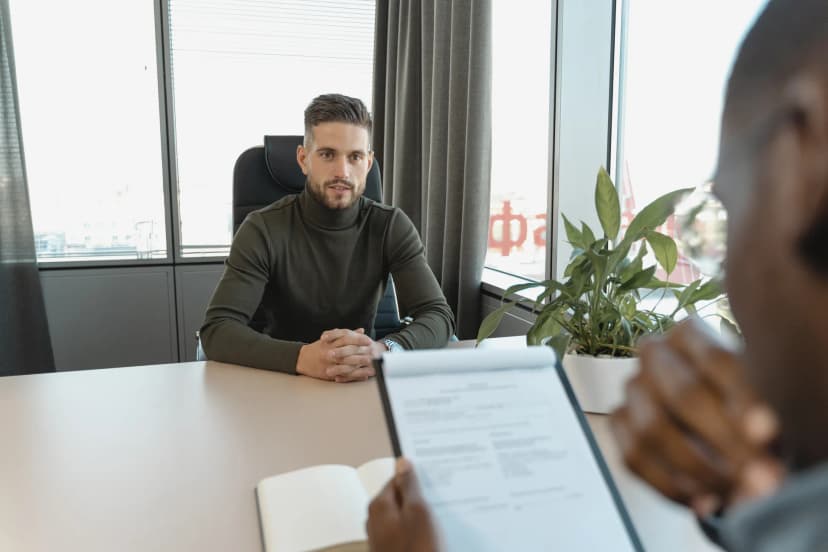 Professional man in turtleneck at office desk during an interview.
