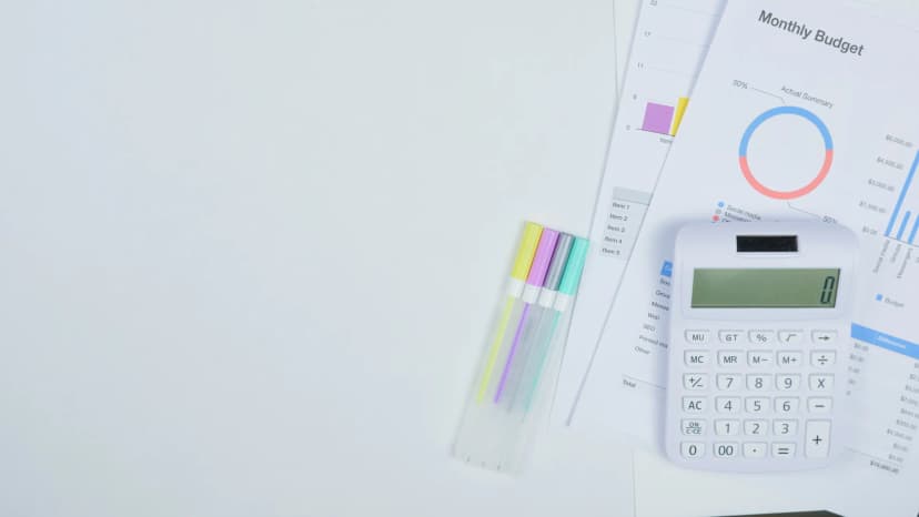 Minimalist office desk with a calculator, budget planning documents, and colorful pens.