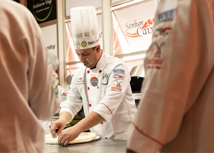 A chef in uniform preparing dough in a professional kitchen setting.