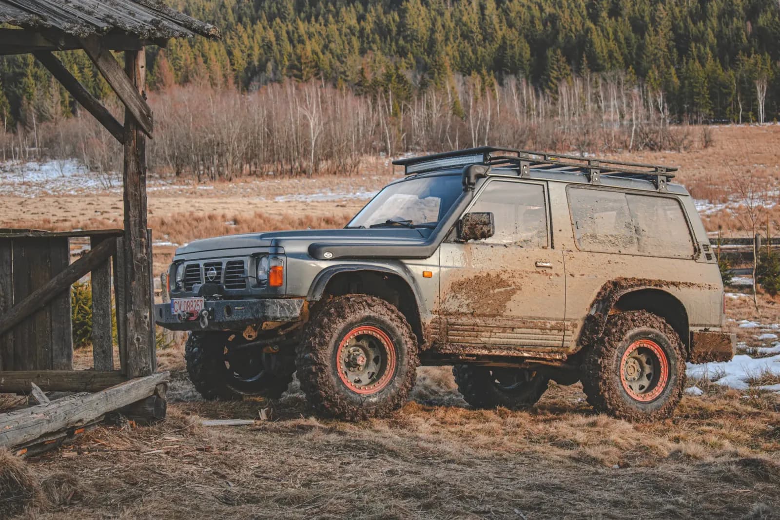 4x4 SUV parked on a muddy trail in Covasna, Romania, amidst a scenic wooded landscape.