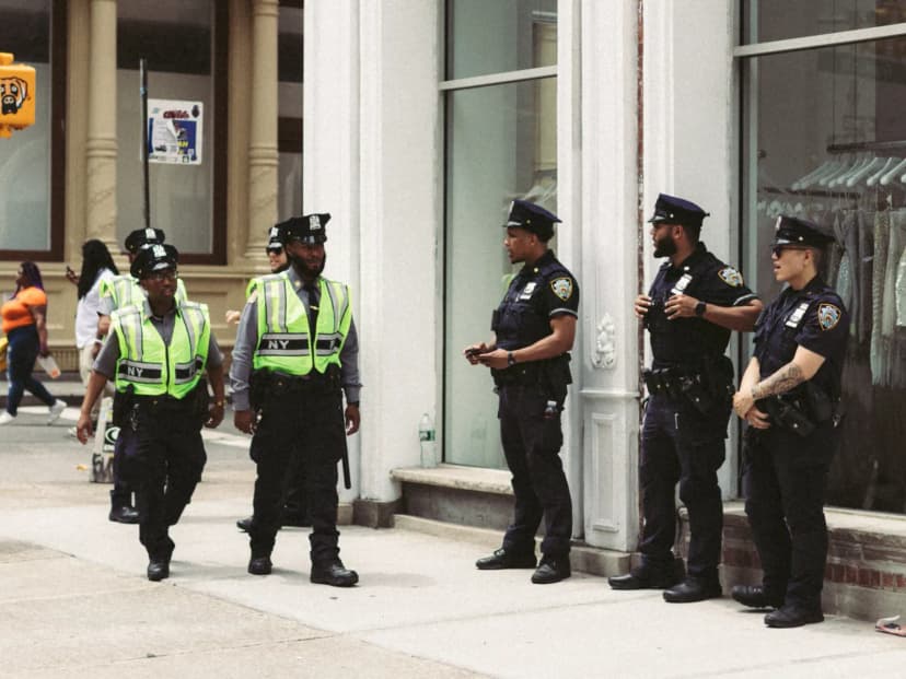 NYPD officers in uniform monitor a busy city street in daytime, ensuring public safety.