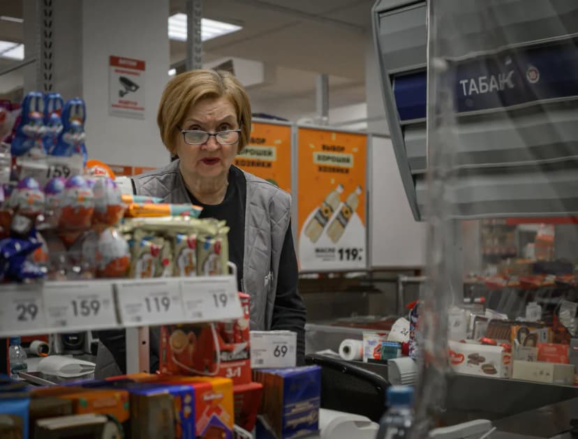 Supermarket scene with cashier and assortment of products at checkout counter.