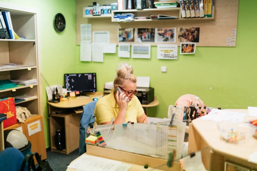 A caregiver talking on the phone at a nursing home reception desk in Karviná, Czech Republic.