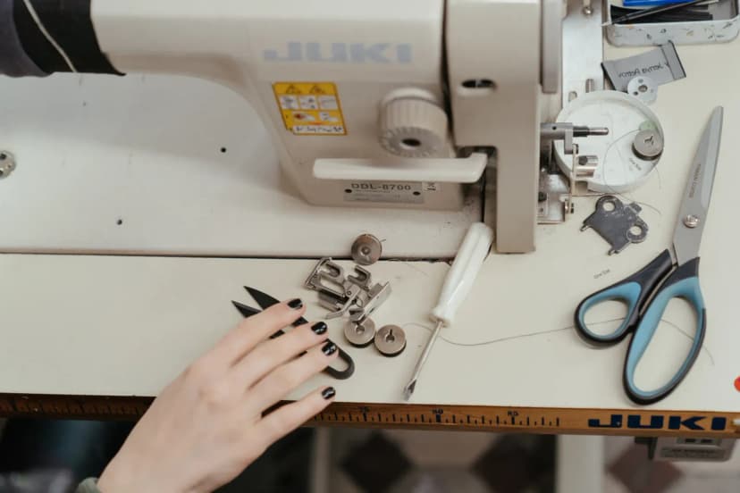 Detailed view of a sewing machine and tools on a workspace, highlighting tailoring craftsmanship.
