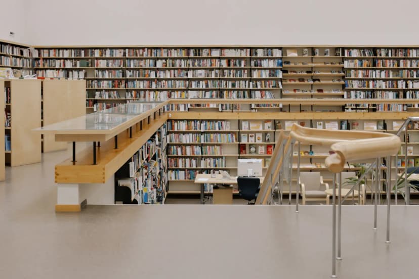 Spacious modern public library interior with tall bookshelves and study areas.