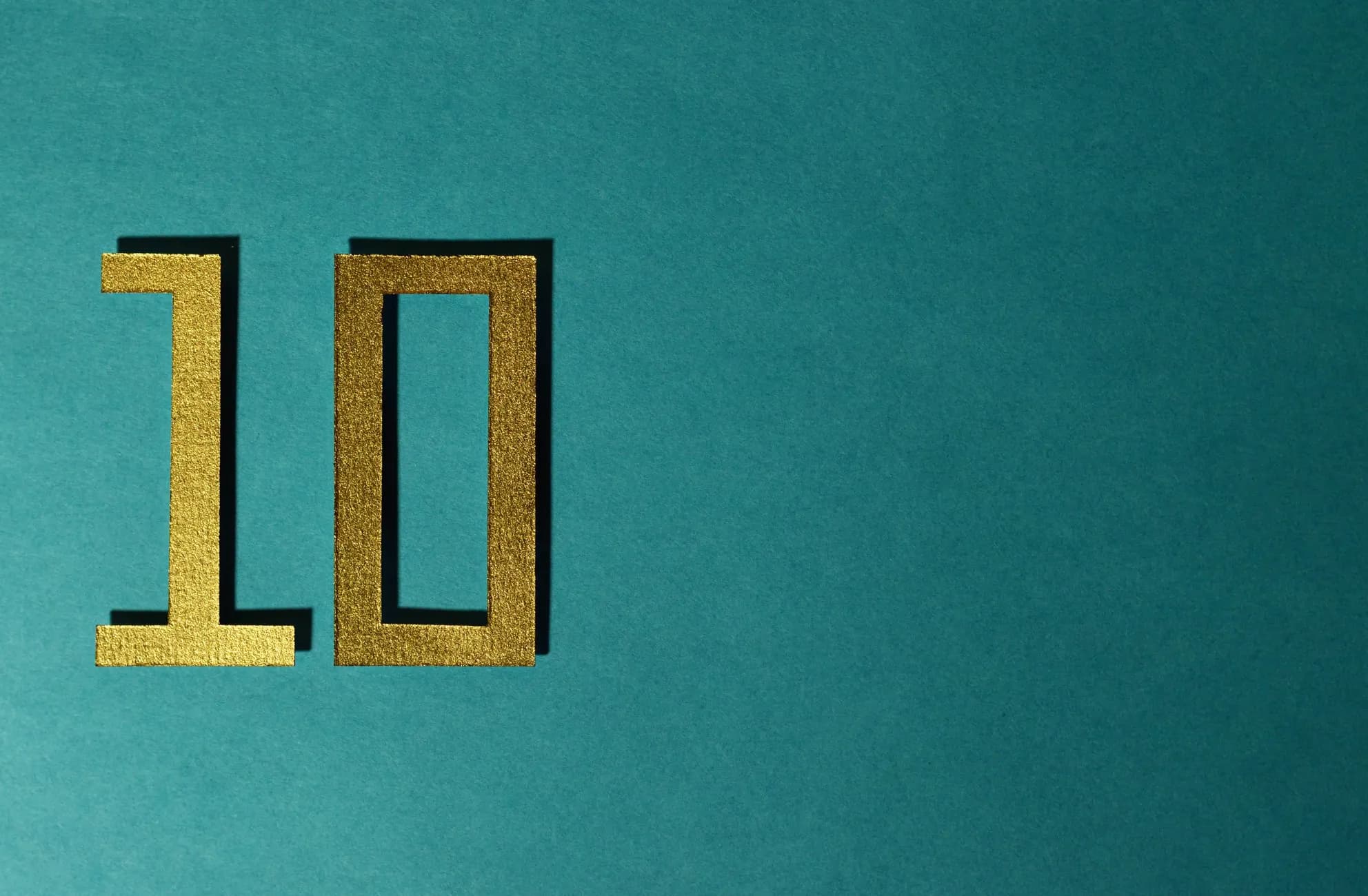 Stylish gold number ten on a textured teal background for design concepts.