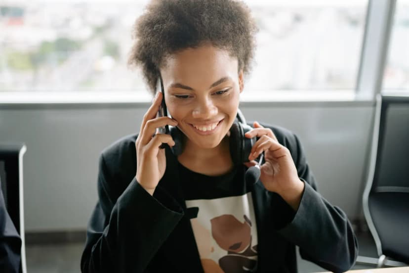 A cheerful call center agent talking on the phone with a headset.