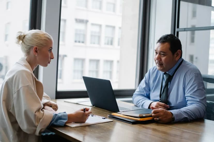 Ethnic boss asking question to female candidate filling information form on clipboard during hiring meeting