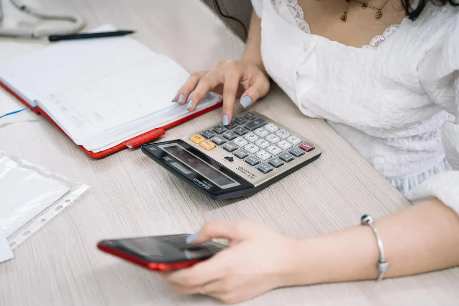 hesap makinesiyle analiz yapan aktüer, veri tablolarını inceleyen finansal kontrolör, modern of of ortamında finans profesyoneli