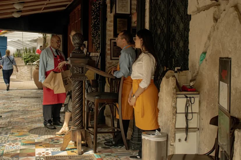 Restaurant staff interacting with customers at entrance, providing a welcoming atmosphere.