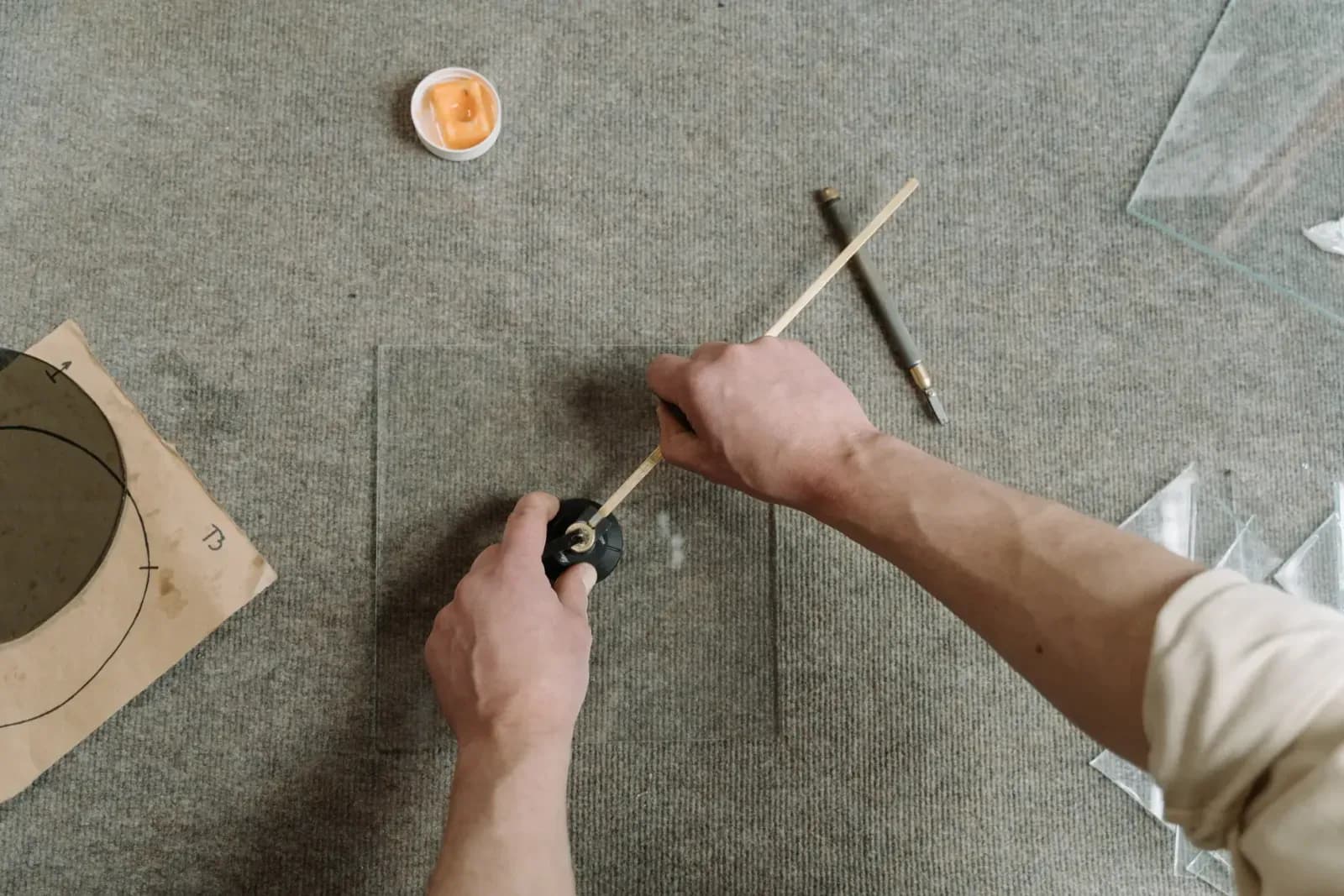 Close-up of artisan hands carefully cutting glass on a workshop table.
