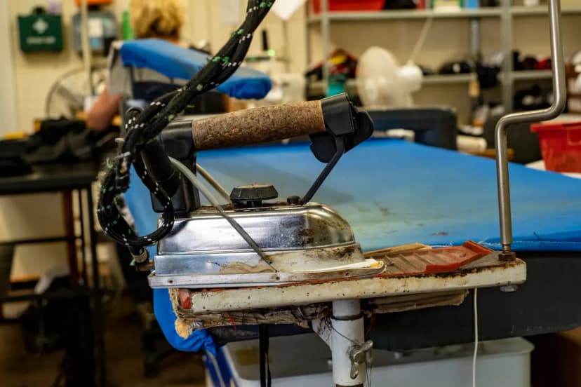 Close-up of a vintage steam iron in a textile workshop with blurred background.